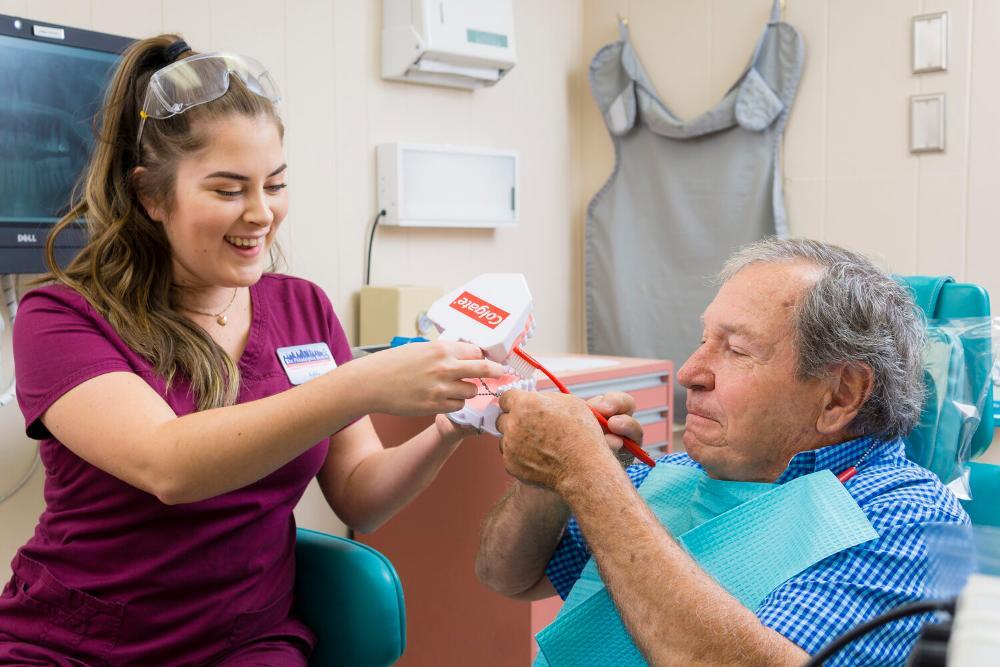 dental assistant demonstrating proper brushing technique 