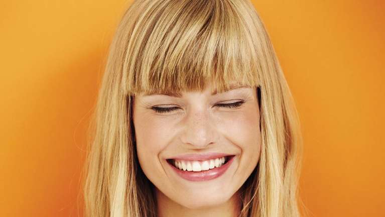 A woman smiling after getting veneers at the Philadelphia Dentist