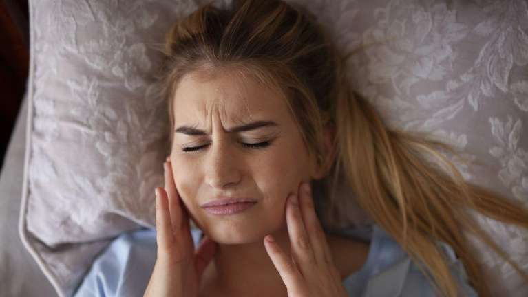 A patient with teeth problem holding her jaws in pain at the Philadelphia Dentist