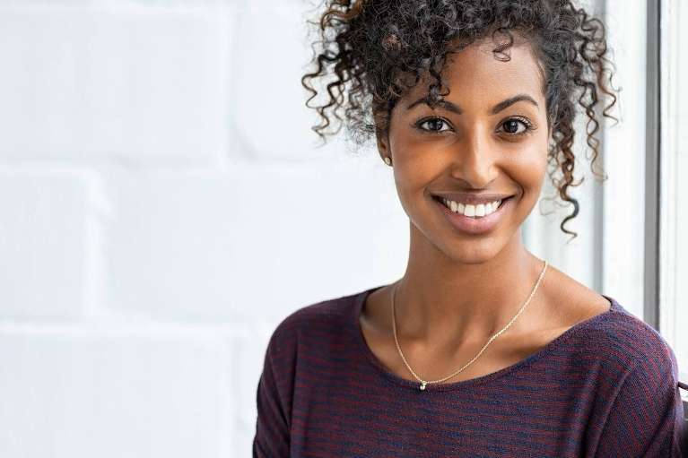 A black woman smiling after getting a Dental Implant in Northeast Philadelphia
