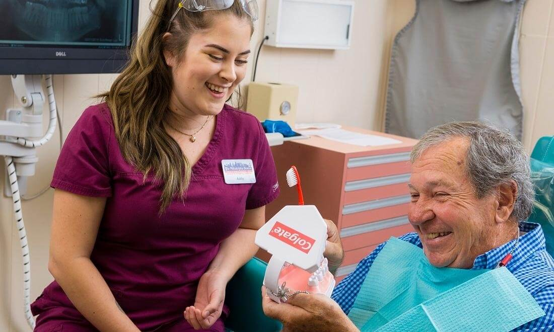 Our dental assistant teaching patient about proper oral health with toothbrush